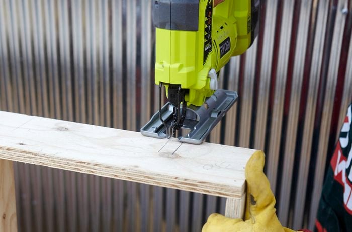 Person using jigsaw to cut slits in timber