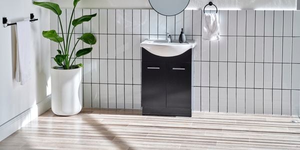 White tiled bathroom with black basin in shot 