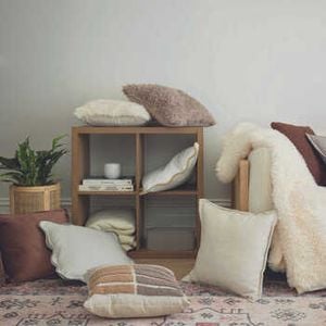 Various cushions and throws lying over a couch and bookself