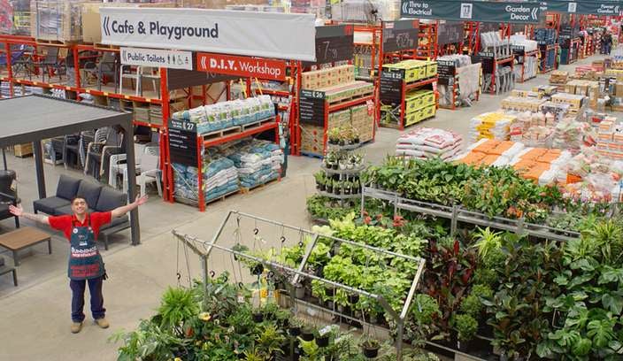 A Bunnings Team Member in a Bunnings store filled with products on dexion and on pallets.