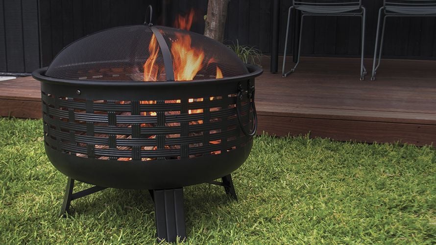 A lit brazier on the lawn in front of a wooden deck