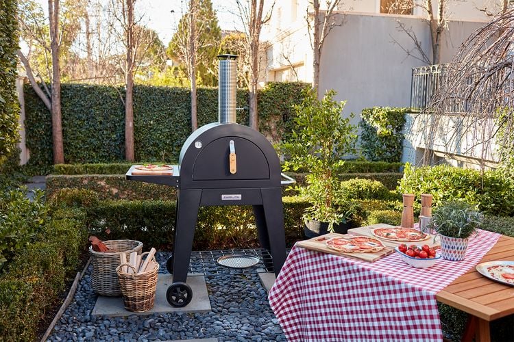 Outdoor dining area with a pizza oven, tomatoes and four very ordinary looking pizzas