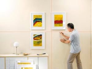 Person using a laser level to hang something up on the wall.