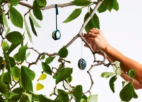 A tree with leaves and painted Easter eggs hanging from string.