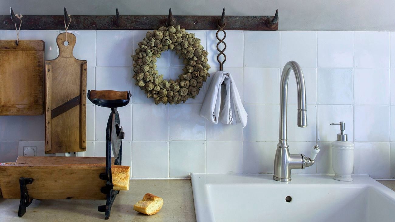 Shot of a kitchen bench featuring cool blue tiles, wooden cutting boards and a hanging wreath.