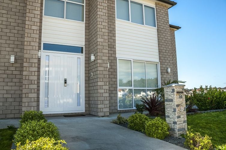 Exterior of a two-storey brick house with off-white trim and a white front door 