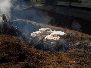 A hole in the ground, with baskets full of hessian sacks inside them.