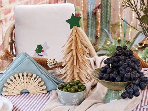A table set with a clothes peg Christmas tree, a napkin holder made from clothes pegs, a kangaroo place holder, and bowls of grapes and olives.