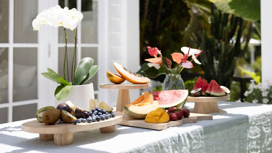 An outdoor table with wooden cutting boards used as serving platters for fruit