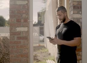 Person looking at their phone whilst standing in-front of a building site.