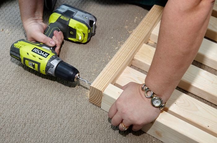 Person drilling timber bed slats into timber beam