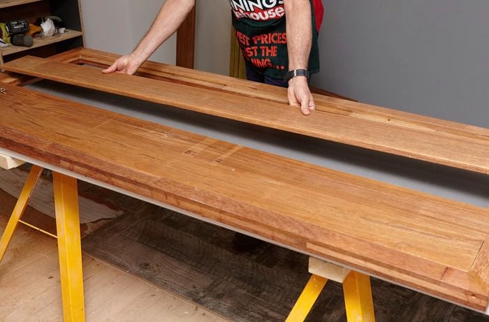 Person laying pieces of timber into a table formation.