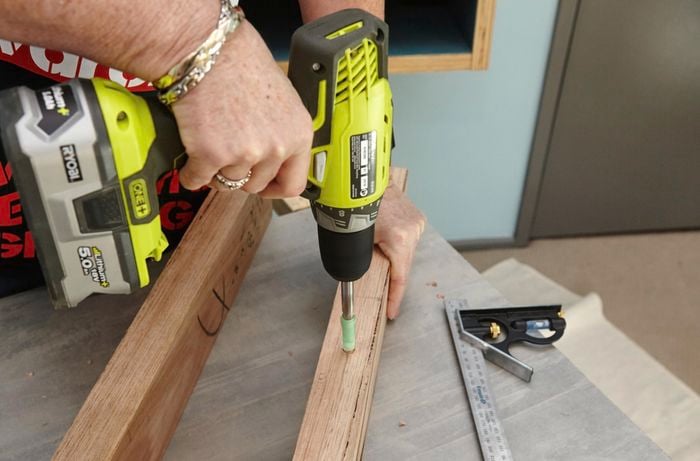 A person drilling a hole in a piece of timber