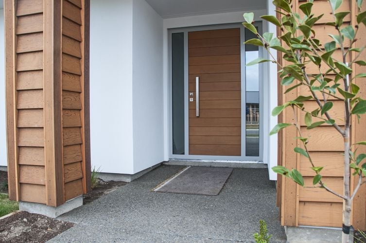 Front entryway to home with large wooden door with steel handle and timber columns
