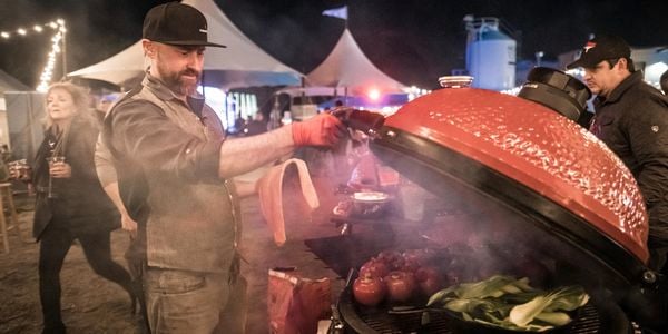 Person opening a Kamado Joe grill showcasing a range of vegetables cooking