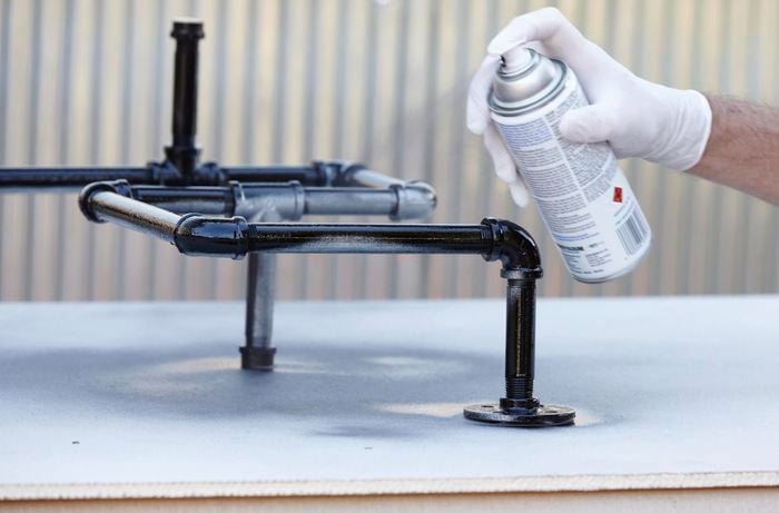 An ironing board storage rack being spray painted black