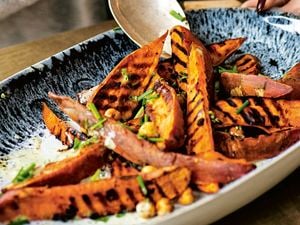 A serving bowl of roasted sweet potatoes with dill ranch dressing.