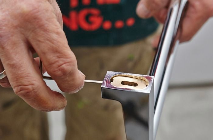 A person using an Allen key to remove the plates from a towel rail