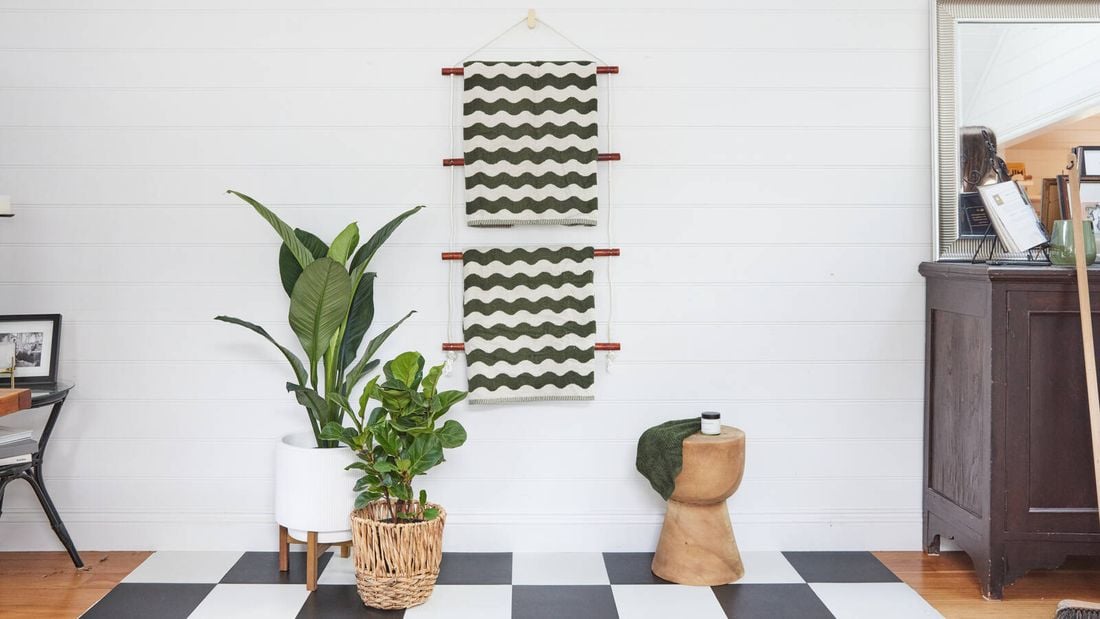 Green and white zig zagged towels hanging on a wooden towel rail on a white tiled wall