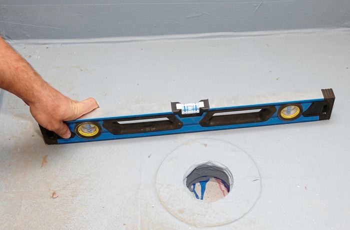 A person holding a spirit level on a shower base