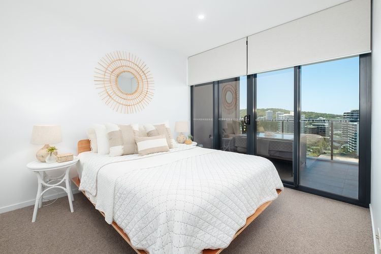 Bedroom in an apartment with white roller blinds partly closed