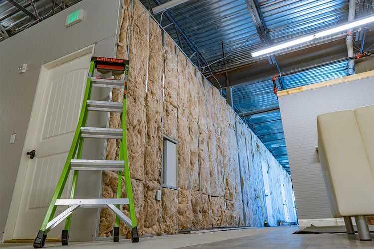 Ladder leaning against wall with exposed insulation