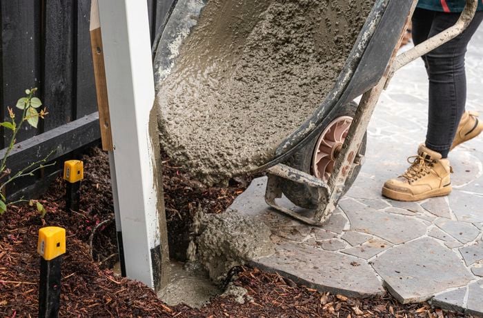 person pouring out concrete from there wheelbarrow