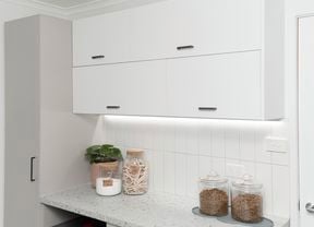 Laundry with lots of cupboards, jars for storage and a plant.