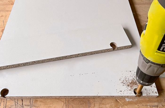 Forstner bit used to drill a hole through a cupboard piece]