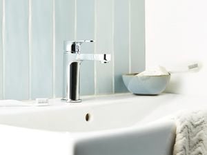 White sink with a bar of soap, a toothbrush and a hand towel on it.