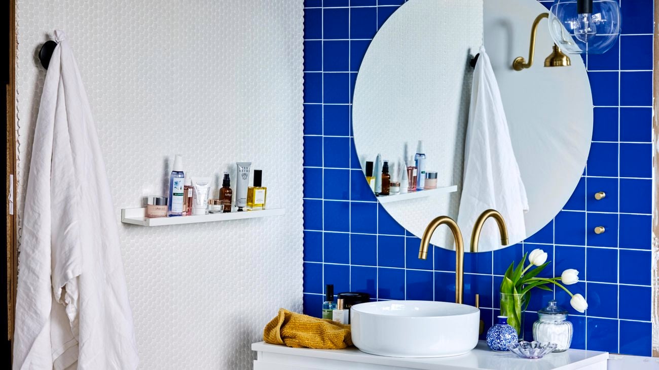Bathroom with interesting blue and white tiled walls, gold tapware.