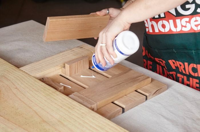 A person applying glue to short lengths of timber