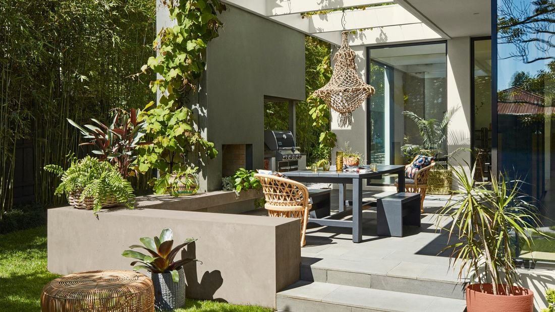 An outdoor space with dining table, paved area and wicker elements