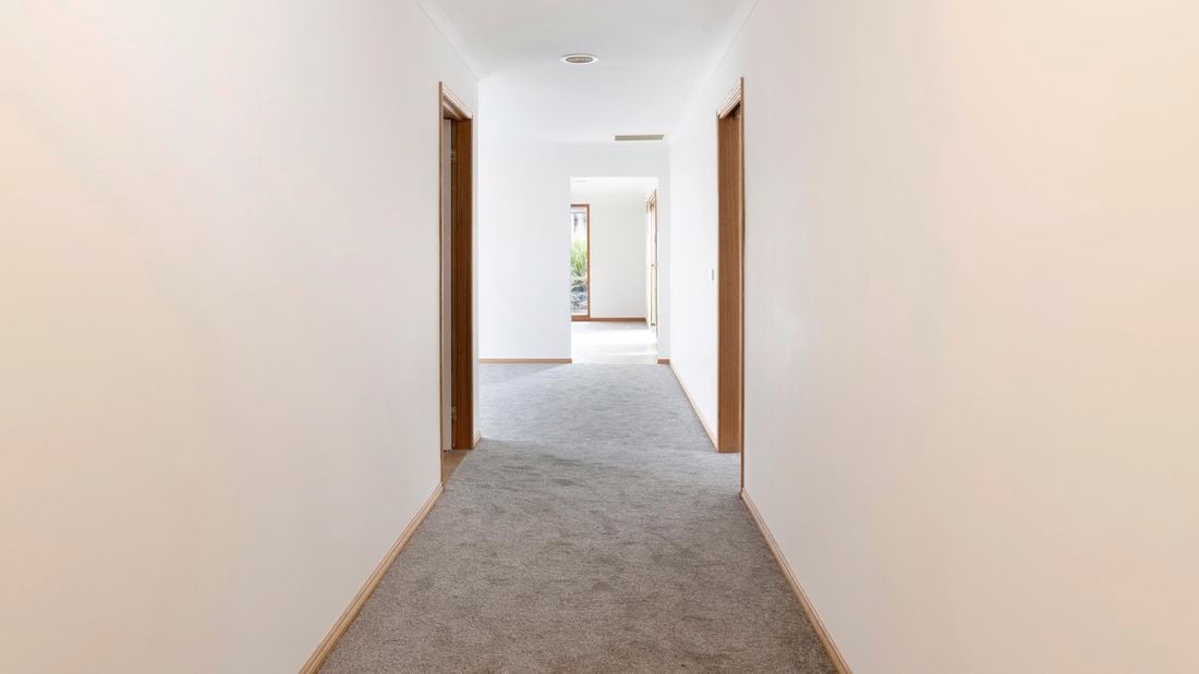 brown carpet in plain hallway entrance with white walls