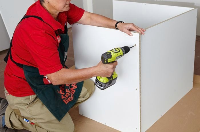 Person drilling screw into panel of cabinet