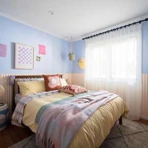 A stylish and functional teenage bedroom with colourful bedding and a decorative rug on hardwood flooring.