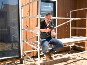 A person sitting on scaffolding outside.