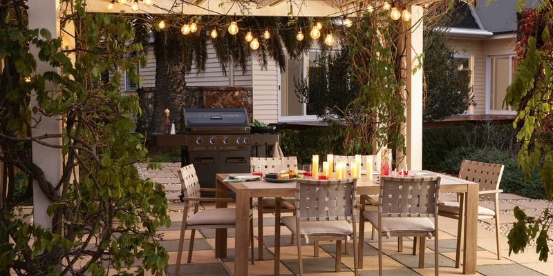 Outdoor entertaining area with a table and chairs, barbecue and party lights.