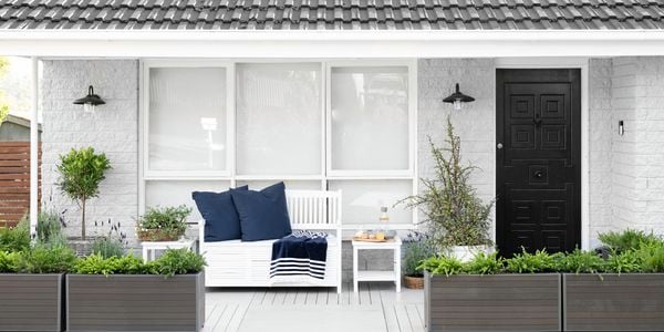 An exterior long shot of a house with freshly painted white timber window frames. 