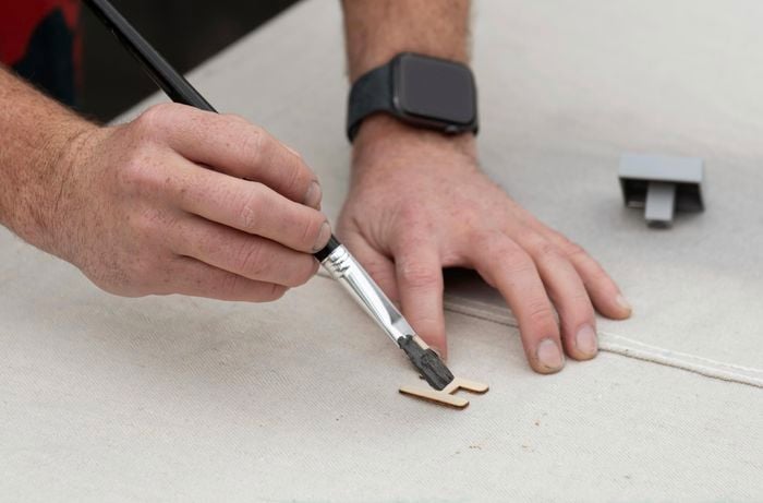 A wooden letter H being painted black with a paintbrush
