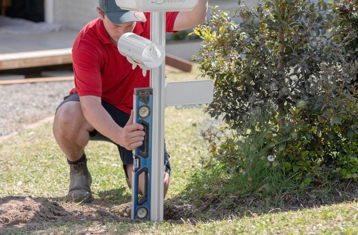 A person checking the post of a letterbox using a spirit level