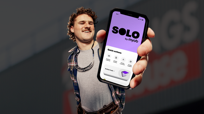A man standing in front of a Bunnings warehouse holding his iPhone up with the Solo by MYOB app.