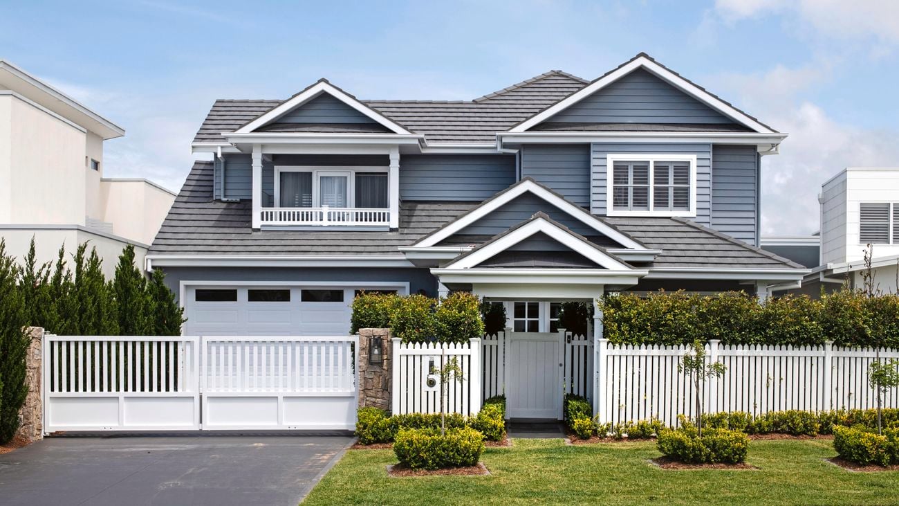 Front exterior of a blue and grey Hamptons-style two-storey house.