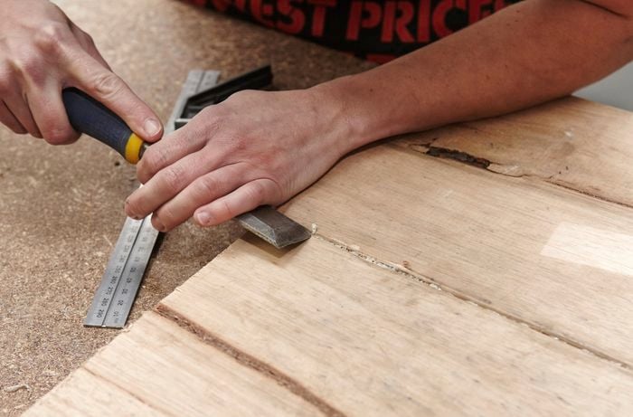 Dried glue being chiselled away from the join between two pieces of wood
