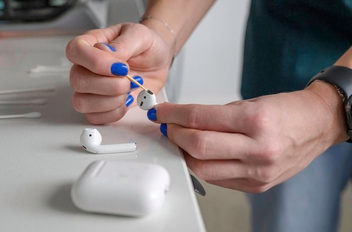 Cleaning airpods with toothpick after spraying it with isopropyl alcohol.
