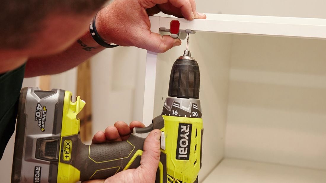 A clasp being secured to the inside of a cupboard