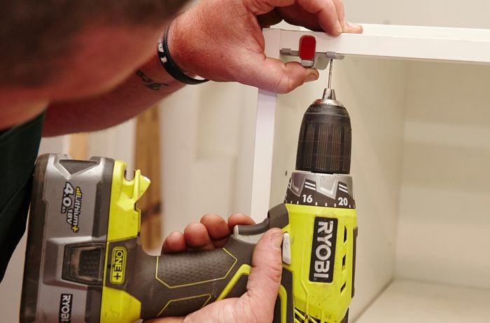 A clasp being secured to the inside of a cupboard