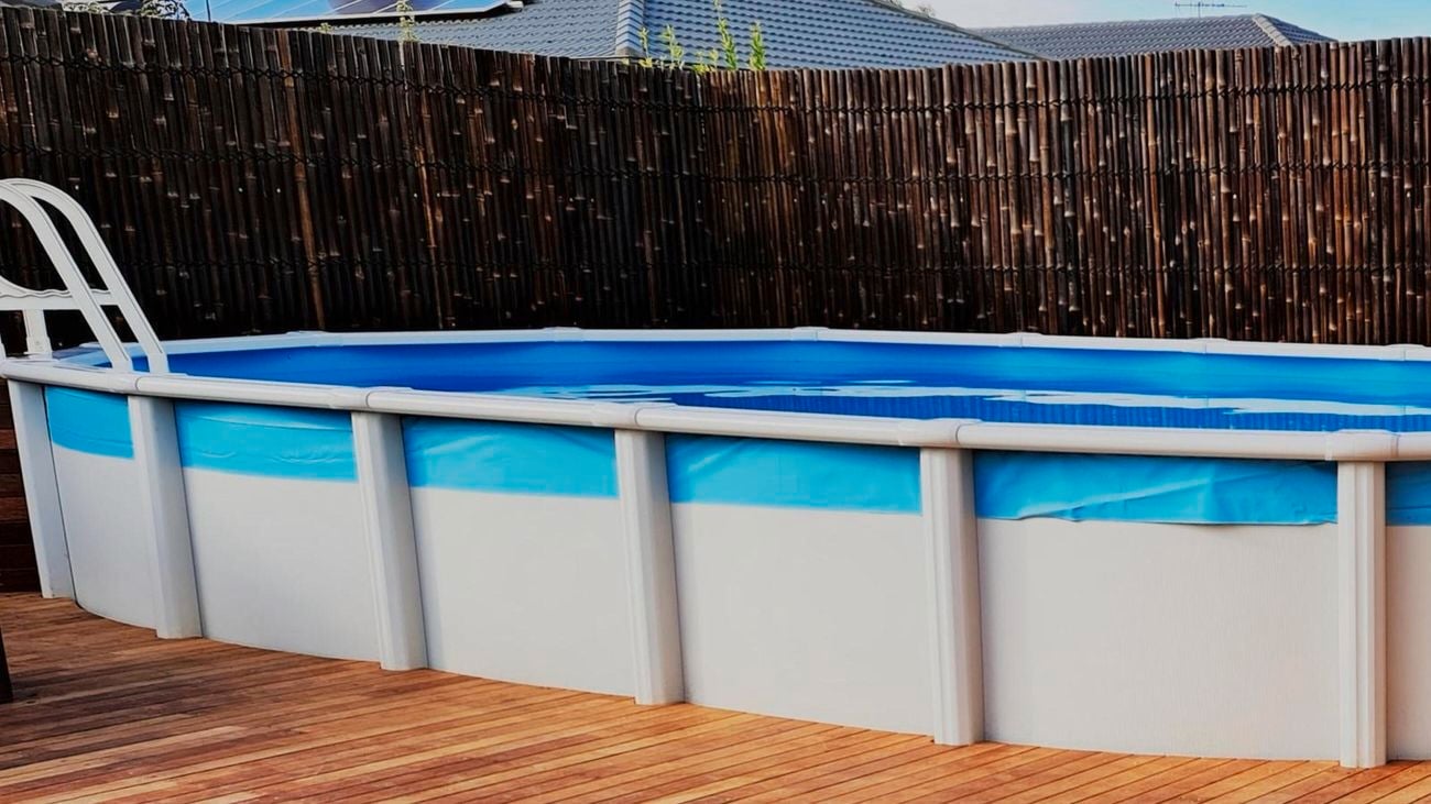 An above ground pool in a backyard with a timber deck around it