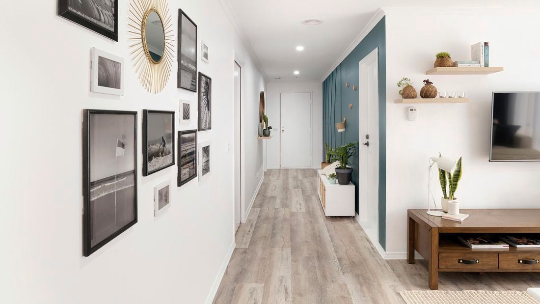 Hallway with timber floor, blue and white painted walls, and lots of paintings and ornaments on the walls.