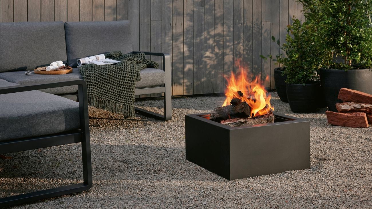 An outdoor setting and a fire pit outside on a pebbled area.